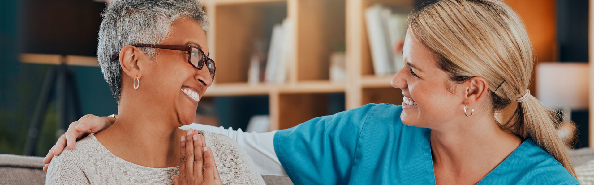 caregiver and elderly woman smiling at each other